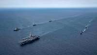 Ein Flugzeugträger und sechs weitere Schiffe fahren in Formation.