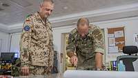 Planung ist alles Ein deutscher und ein österreichischer Soldat stehen in einem Großraumbüro an einem Kartentisch