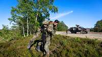 Ein Soldat trägt einen Soldaten auf der Schulter weg von einem Fahrzeug.
