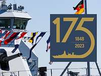 Marine 175 Blick auf das Vorschiff eines grauen Kriegsschiffs; bunte Signalflaggen wehen von einer langen Leine.