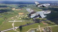 Zwei Tornados fliegen am Himmer in Formation. Unter ihnen ist deutlich der Flugplatz Jagel erkennbar.