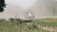 Ein Hubschrauber landet an einem Waldrand.