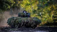 Ein Schützenpanzer Puma fährt mit erhöhter Geschwindigkeit über einen Waldweg.