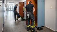 Zwei Männer ziehen sich ihre Feuerschutzkleidung an.
