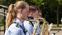 Soldatinnen und Soldaten spielen auf Blasinstrumenten