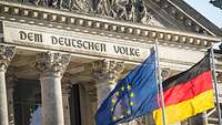 Detailblick auf ein großes, graues Steingebäude; zu lesen ist die Inschrift: dem deutschen Volke.