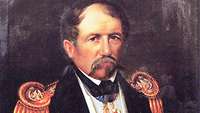 Portraitbild eines Marineoffiziers mit Schnurrbart, in dunkelblauer Uniform mit goldenen Epauletten.