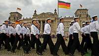 Marinesoldaten in Matrosenuniform marschieren vor dem Reichstagsgebäude.