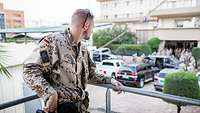 Ein Soldat steht auf einem Balkon und schaut auf eine Menschenmenge herunter.