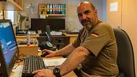 Ein Soldat sitzt am Schreibtisch am Computer. 