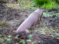 Die Sprenggranate einer Panzerhaubitze liegt im Gelände auf dem Truppenübungsplatz