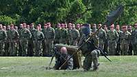 Zwei Soldaten steigen mit dem Kompaniewimpel aus einem Erdloch.