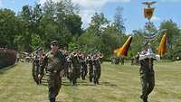 Auf einer Wiese sind Abordnungen von Soldaten von anderen Standorten mit ihren Wimpeln angereist.