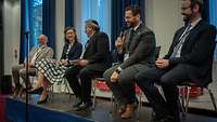 Vier Männer mit Kippa und eine Frau sitzen auf einem Podium und unterhalten sich