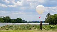 Soldat auf Wiese startet einen Messballon
