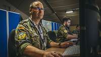 Soldat mit Air Defender Patch sitzt vor einem Computer