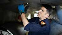 Der technische Offizier Christos G. öffnet eine Klappe am Rumpf der F-16
