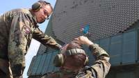 Zwei Soldaten tauschen gemeinsam ein Antennenelement am Radar aus.