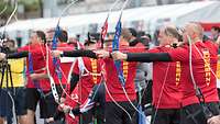 Mehrere Sportler schießen mit Pfeil und Bogen