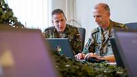Zwei Männer sitzen am PC und besprechen sich.