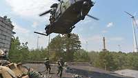 An einem Seil lässt sich ein Soldat von einem Hubschrauber auf ein Dach ab. Zwei sind schon dort.