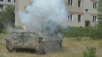 Ein Panzerfahrzeug ist in Rauch eingehüllt, Flammen sind zu sehen.