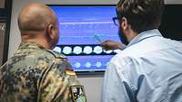 A soldier and a civilian at a screen