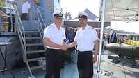 Zwei Marinesoldaten stehen an Bord eines Bootes und schütteln sich die Hand.