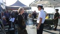 Ein Marinesoldat spricht mit einer blonden Frau an Bord eines Bootes.