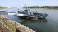 Ein graues Boot hat an einem Steg angelegt.