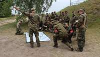 Soldaten schauen auf eine Lagekarte die auf dem Boden liegt. Ein Soldat zeigt dabei in eine Richtung