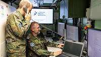 Zwei Soldaten arbeiten in einer Funkkabine. Einer von Ihnen ist am telefonieren.