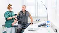 Untersuchung_PVD Frau in Berufskleidung einer Medizinisch-technischer Assistentin misst Blutdruck bei einem Patienten