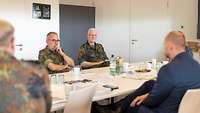Fünf Personen sitzen um einen Tisch für eine Besprechung
