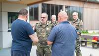 Drei Männer stehen sich gegenüber und unterhalten sich