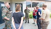 Eine Gruppe von sechs Männern und eine Frau steht im Kreis und unterhält sich