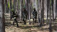 Mehrere Soldaten gehen durch den Wald