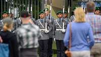 Soldaten vom Wachbataillon stehen in Formation, interessierte Besucher schauen dabei zu