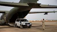 Ein Soldat weist ein gepanzerten Geländewagen in das Transportflugzeug Transall C-160 ein 