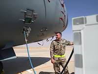 Wasserversorgung Ein Soldat steht vor einem Flugzeug, an dem ein Wasserschlauch angebracht ist.