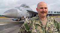 Ein Mann in amerikanischer Uniform vor einem grauen Jet.