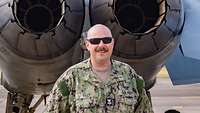 Ein Mann in amerikanischer Uniform, mit Sonnenbrille, hinter einem Jet.