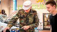 Ein Soldat in Uniform versucht sich beim Feilen eines Stahlblocks.