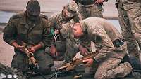 Ein deutscher und ein litauischer Soldat setzen ein MG 5 zusammen.