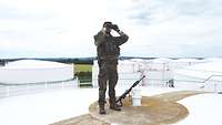 Soldat mit Fernglas auf dem Dach eines Chemieterminals