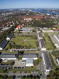 Eine Stadt aus der Vogelperspektive. Zahlreiche Gebäude und Bäume sind zu sehen.