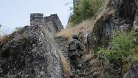 Ein Soldat geht die Treppen einer alten Burg hinauf.