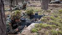 Soldaten liegen in ihren Stellungen im Wald