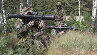 Zwei Soldaten kniend im Wald mit Panzerfaust im Anschlag.