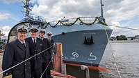 Vier Soldaten posieren am Kai vor einem mit Girlanden geschmückten Schiff